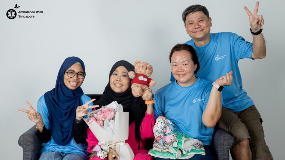 Ambulance Wish Singapore volunteers celebrate with a patient holding flowers and a teddy bear