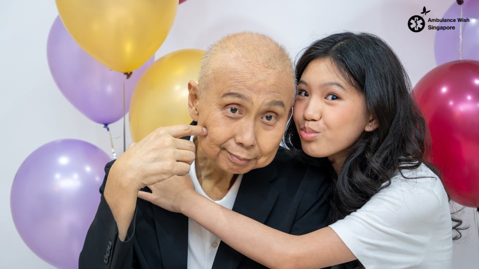 A terminally ill patient smiles with his granddaughter surrounded by balloons at a birthday wish celebration