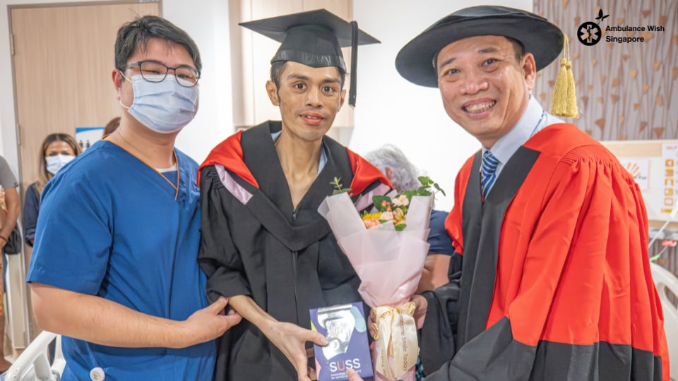 A patient in cap and gown receives his degree at a bedside graduation ceremony